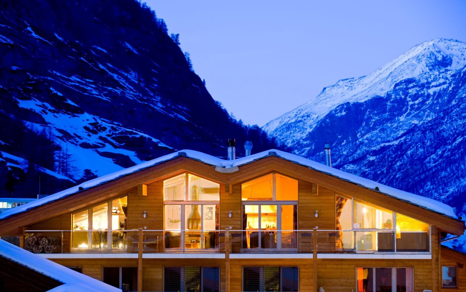 Chalet exterior with upper-level balcony and mountain views at dusk