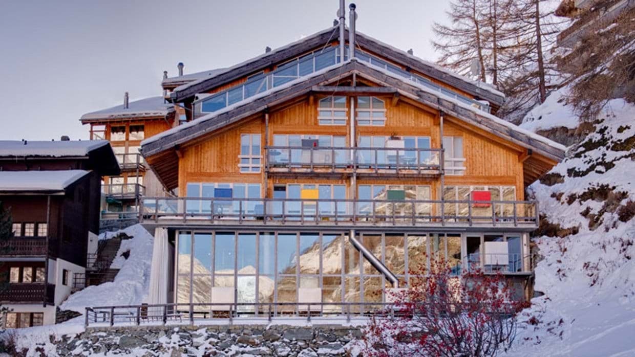Ski-in chalet exterior with multi-level glass balconies and mountain views