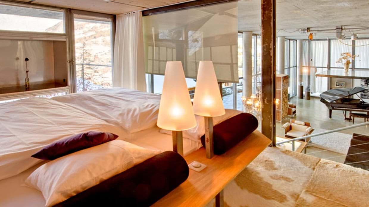 Loft bedroom overlooking main living area with grand piano and floor-to-ceiling windows