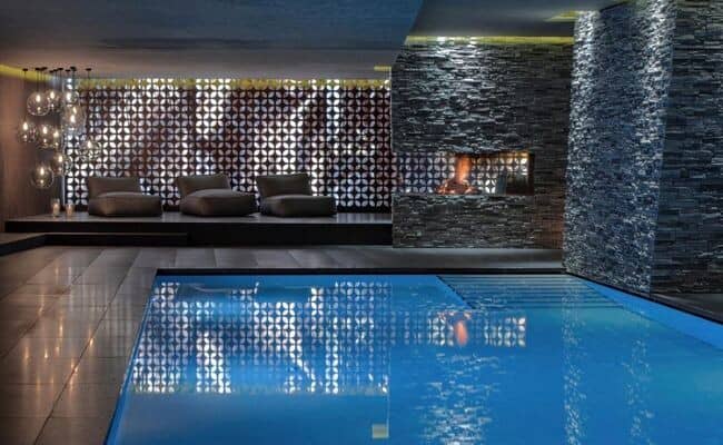 Indoor heated pool with stone fireplace and poolside lounge area
