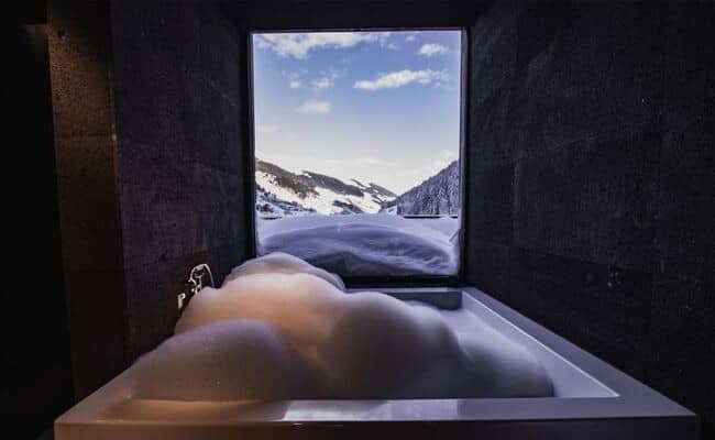Soaking tub with picture window and snow-capped mountain views