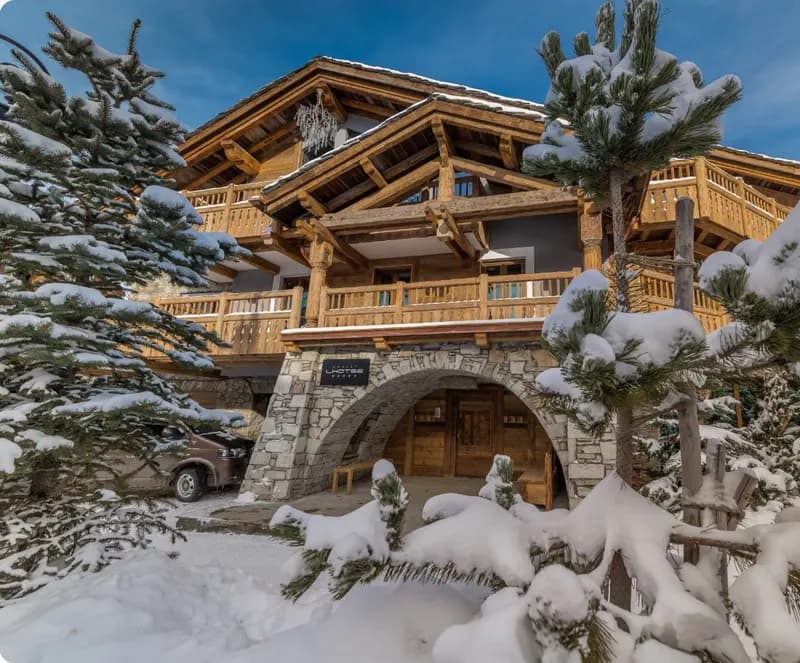 Timber chalet under fresh snow, framed by snow-laden pines
