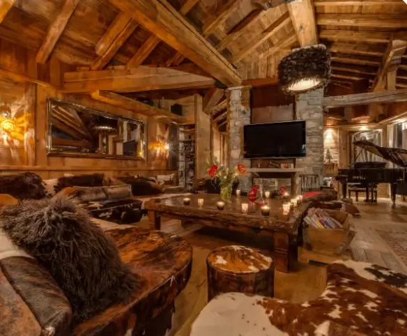 Chalet living room with timber beams, a stone chimney and a candlelit table