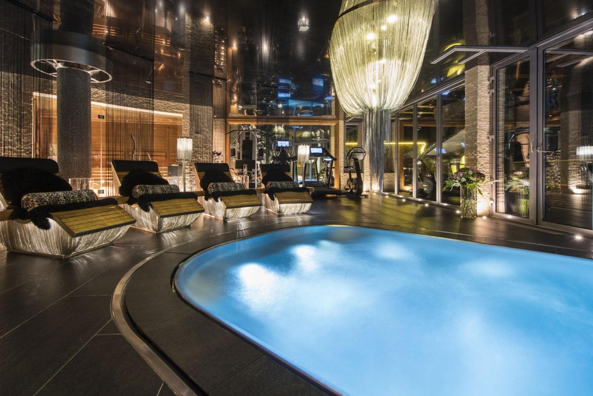 Indoor pool and lounge area with adjacent fitness center and sauna