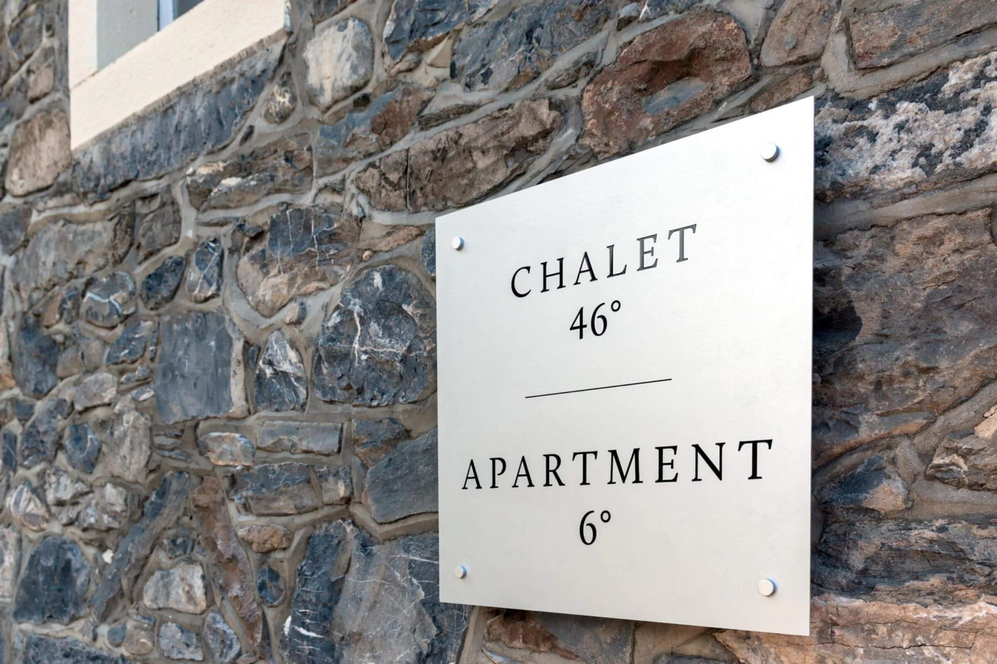Stone exterior entrance with signs for the apartment and neighbouring chalet