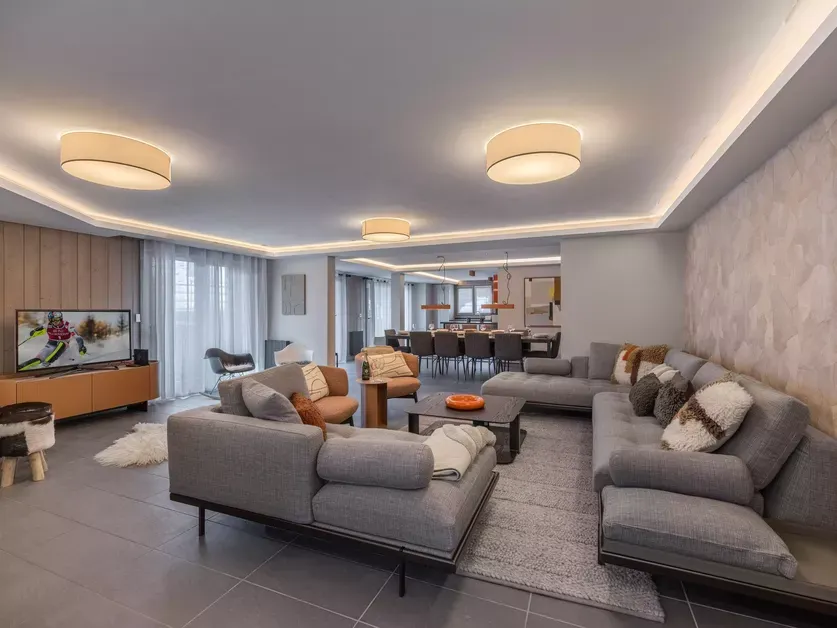 Open-plan lounge with three sofas, a television and the dining area beyond