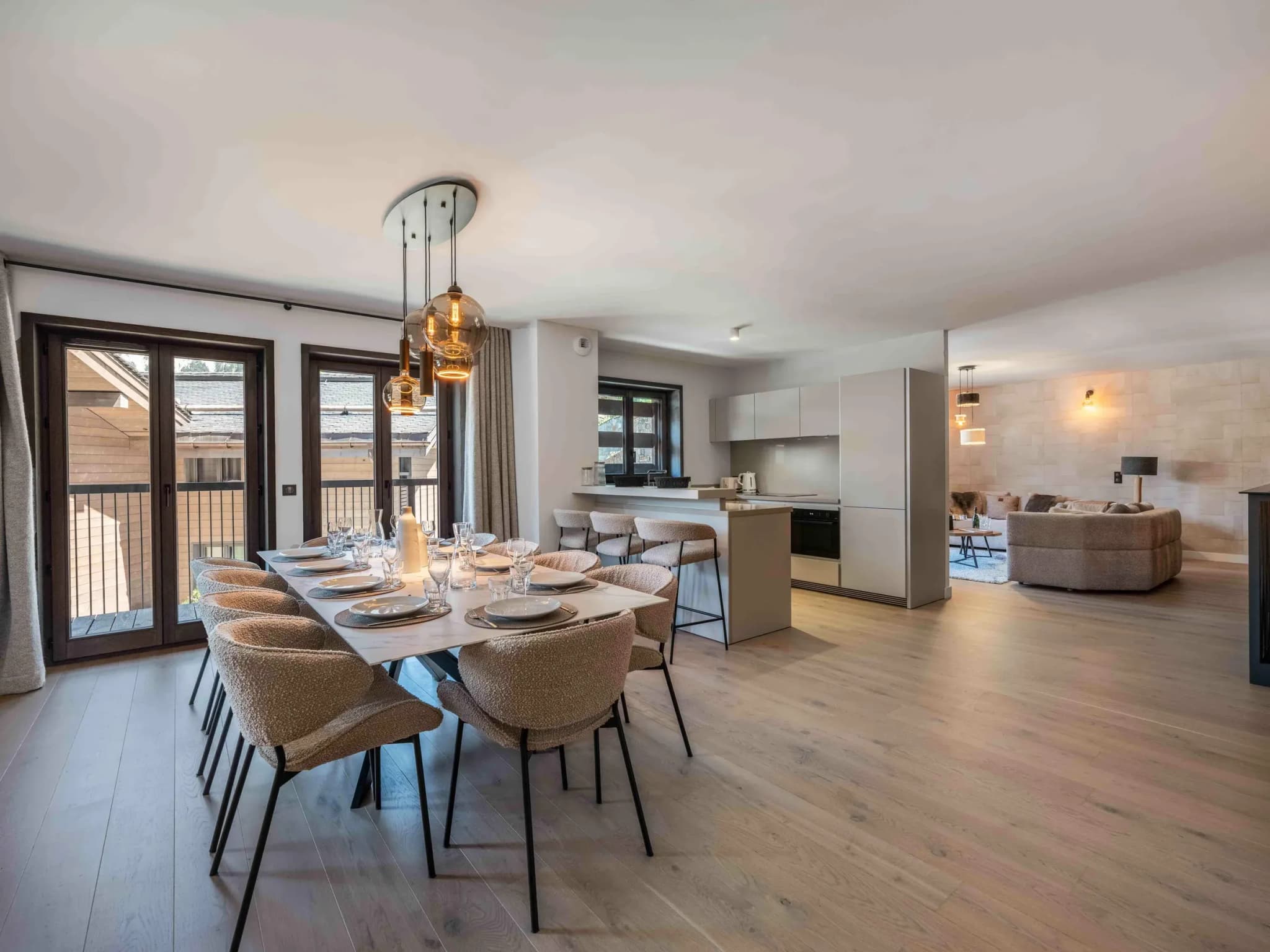 Dining area with ten-seat table, glass pendant lights and balcony doors, open to kitchen and lounge