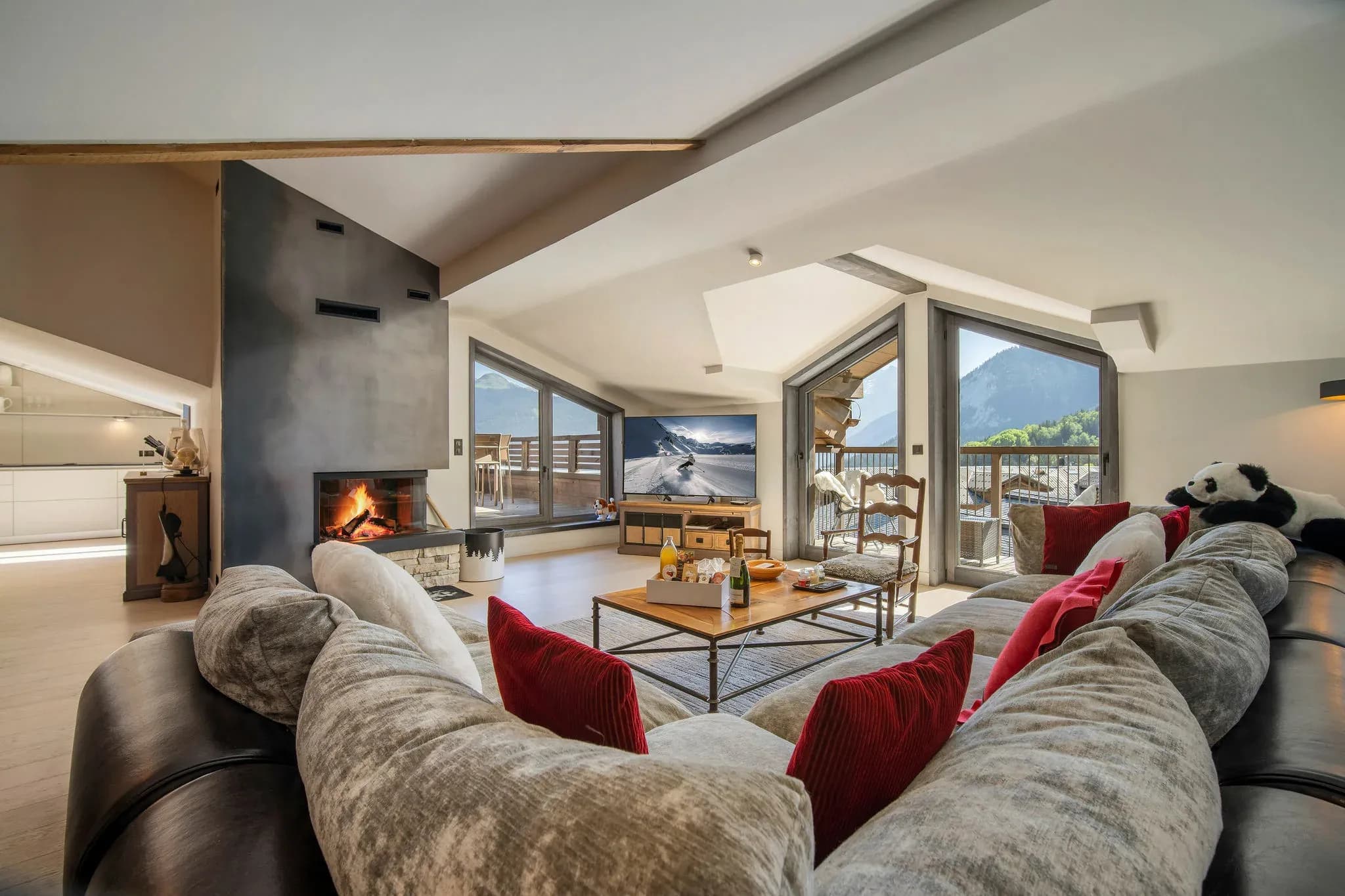 Living room with corner sofa, open fireplace and mountain views through balcony doors