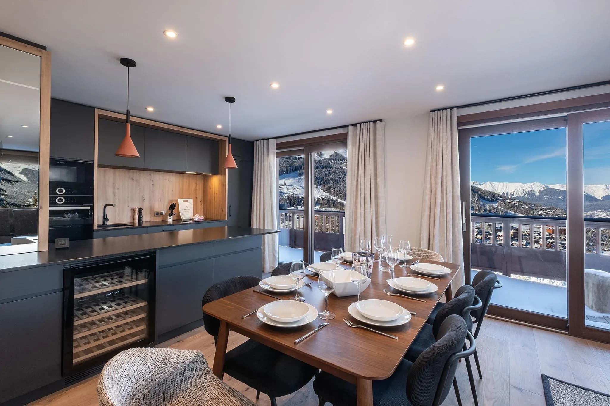 Dining table set for six beside kitchen island with wine fridge and balcony views