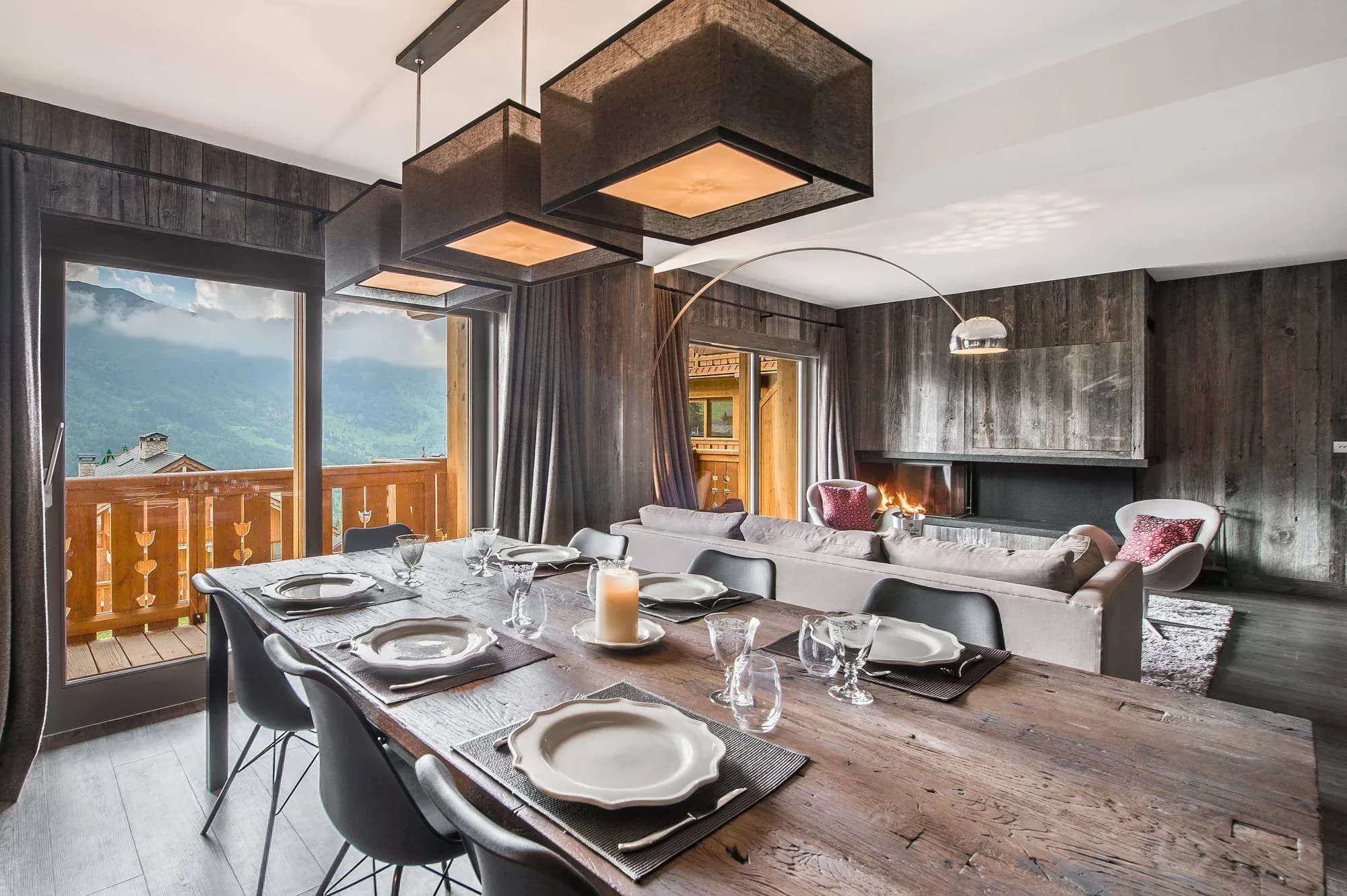 Dining table with six chairs, open to lounge with fireplace and mountain views