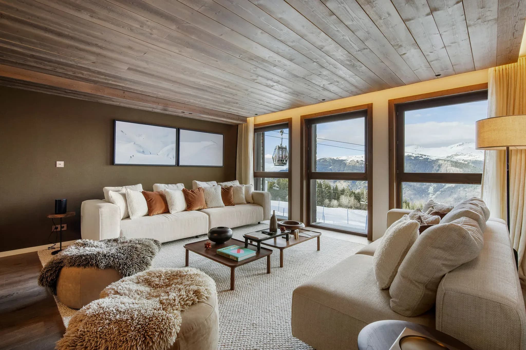 Lounge with two sofas, sheepskin pouffes and mountain-facing windows