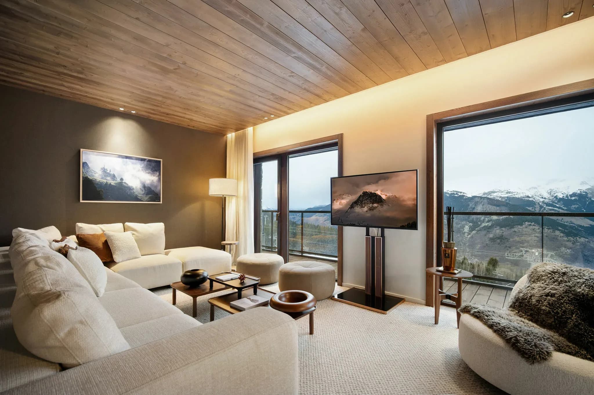 Living room with large corner sofa, TV and floor-to-ceiling windows facing the mountains