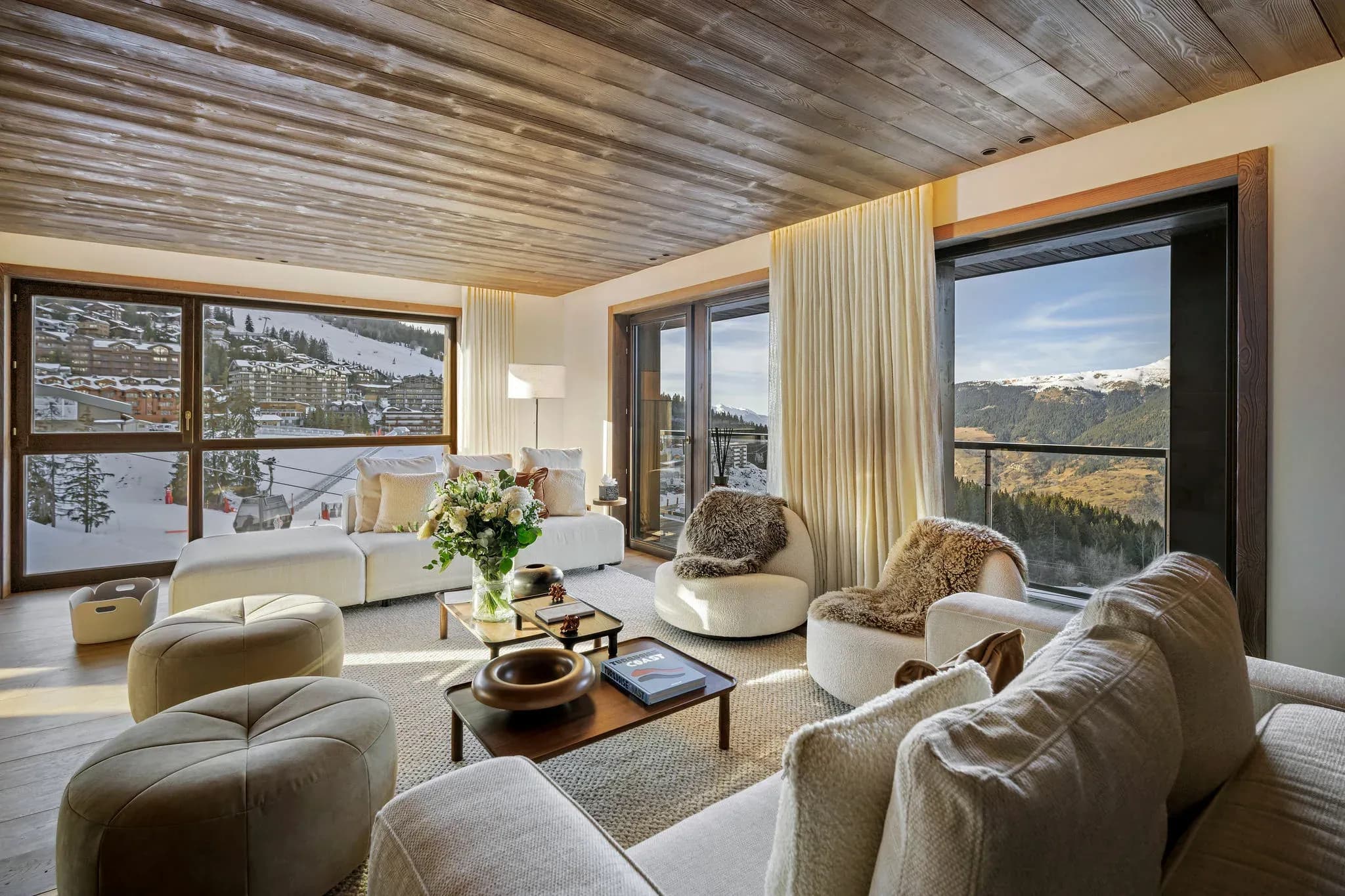 Living room with sofas, swivel armchairs and floor-to-ceiling windows over the slopes and gondola