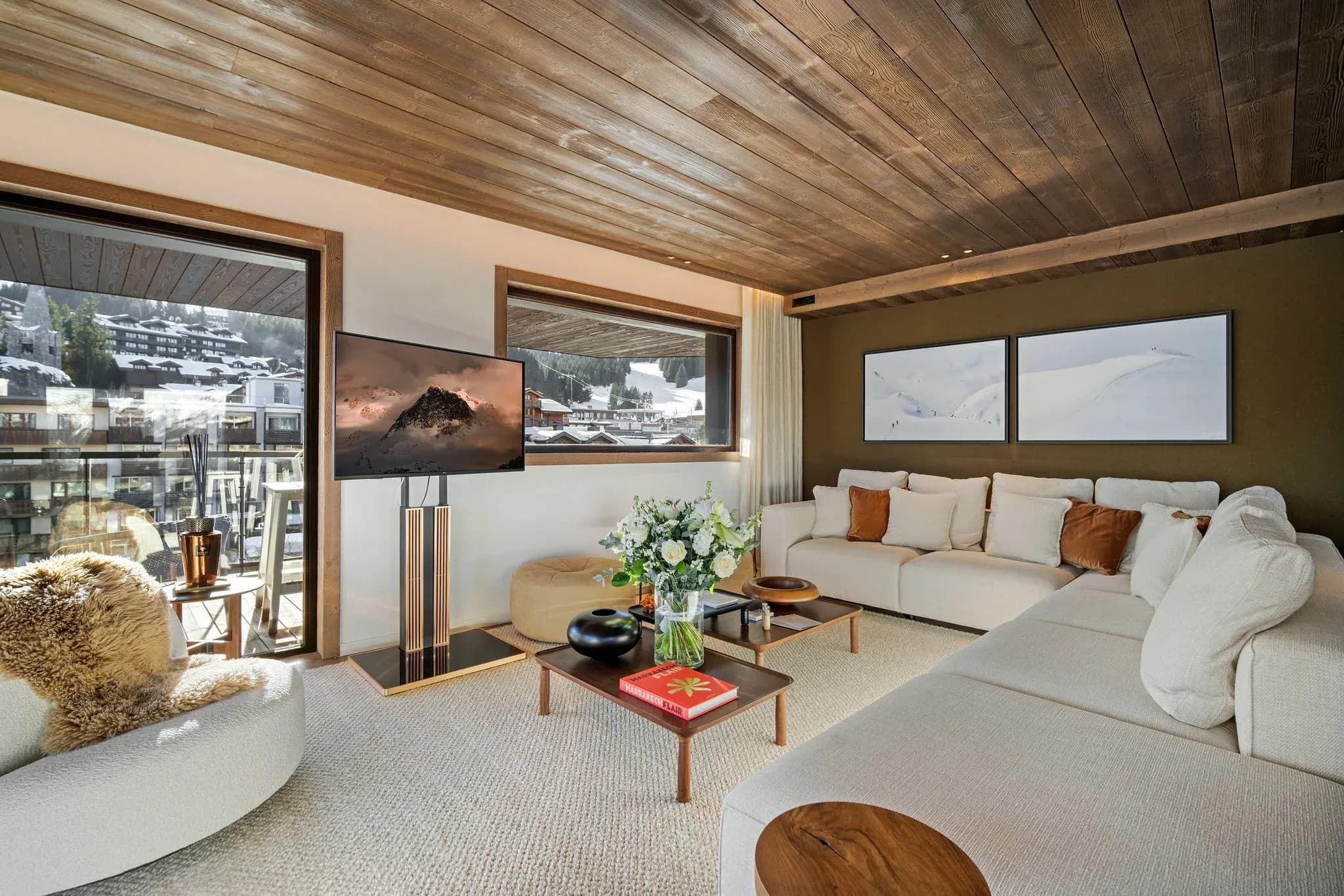 Living room with L-shaped sofa, wall-mounted TV and village view