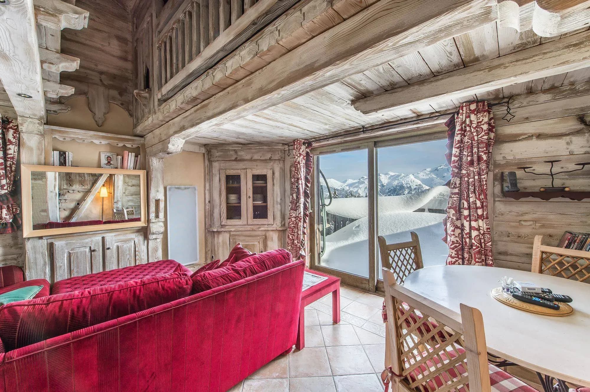 Living room with red sofa, round dining table and sliding door to snowy mountain view