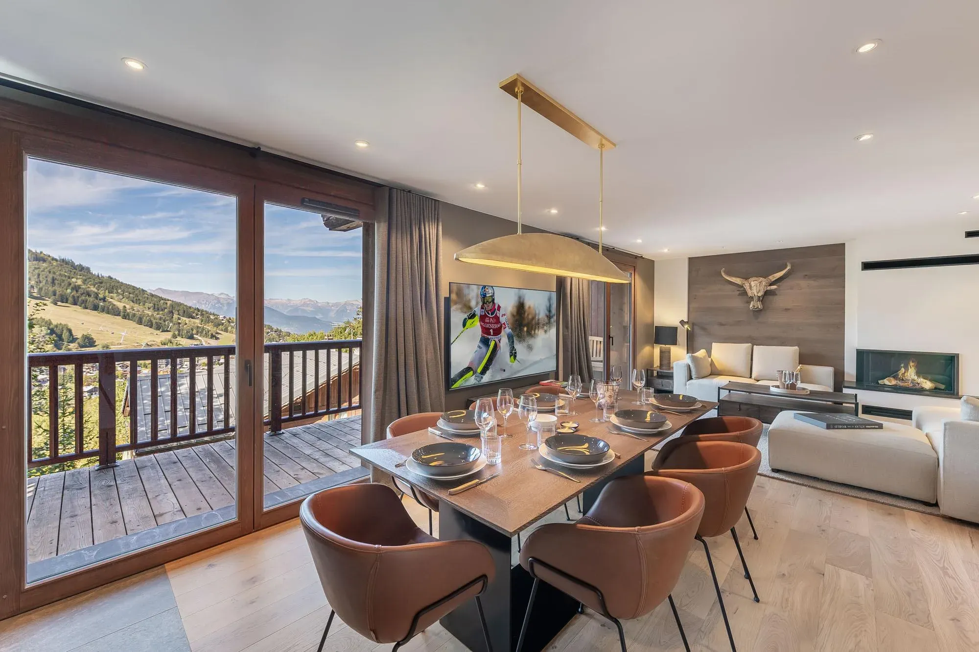 Dining table with six leather chairs beside balcony doors with slope views