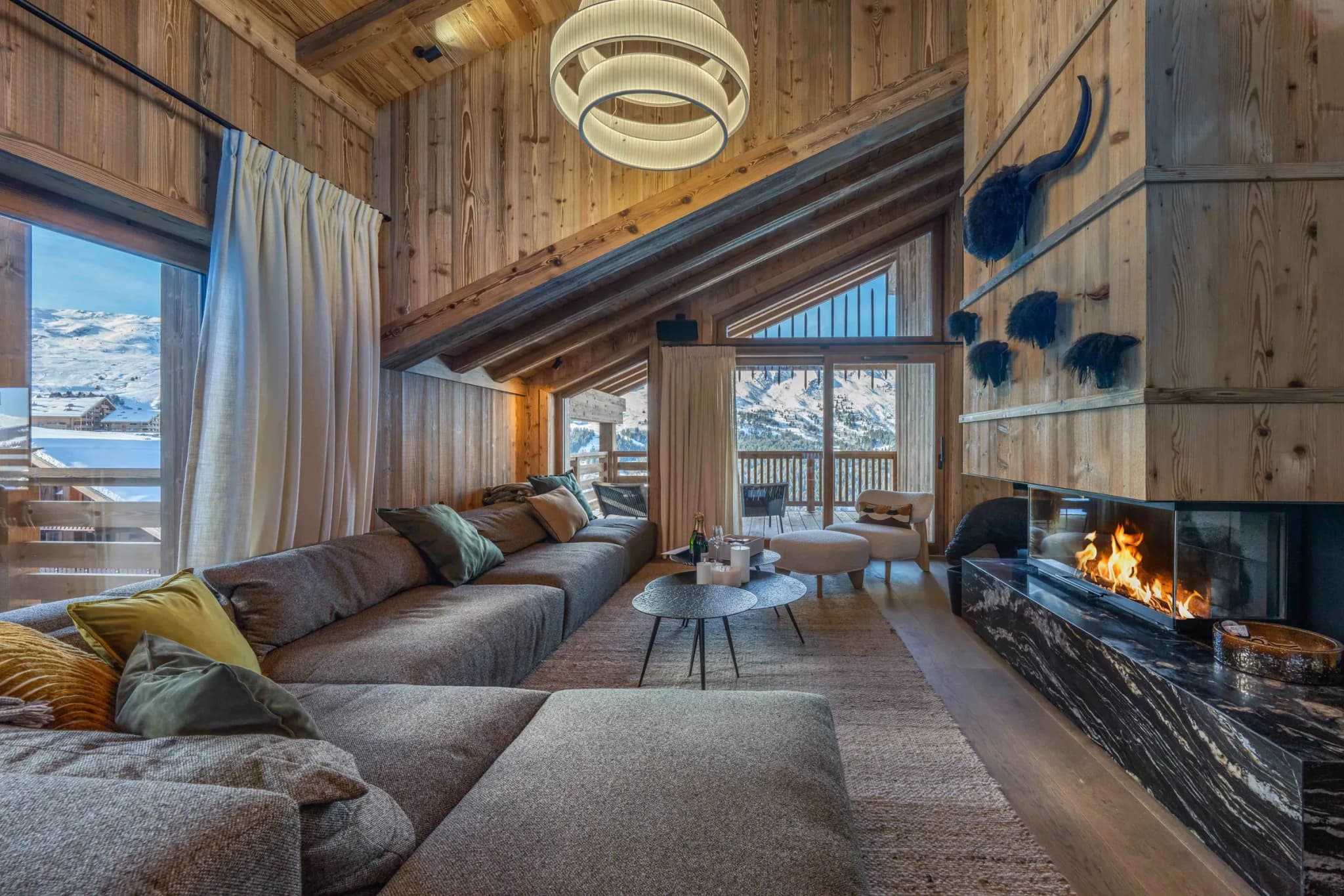 Lounge with large corner sofa, glass-fronted fireplace and mountain view