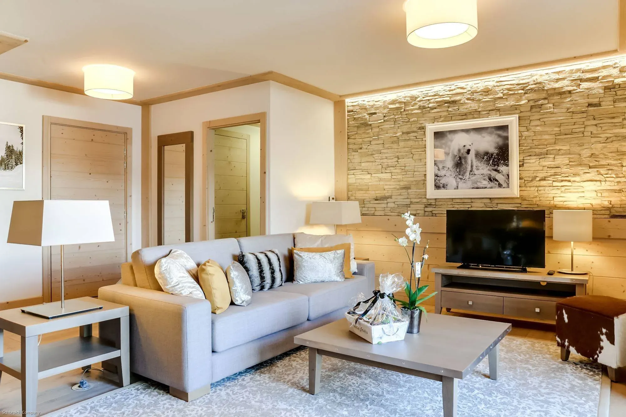 Living room with grey sofa, stone feature wall and TV on wooden unit