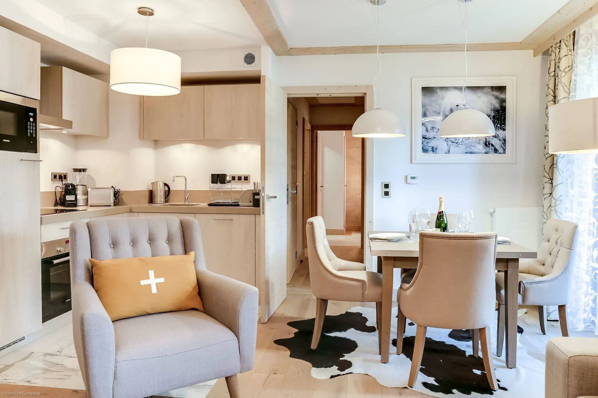 Open-plan kitchen and dining table with four upholstered chairs, armchair in foreground