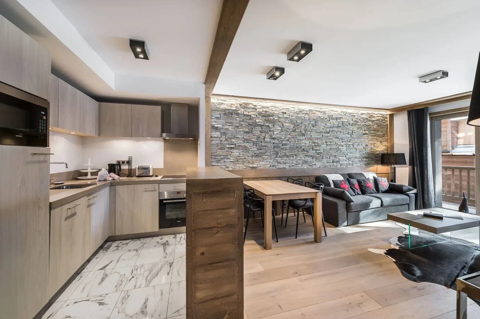 Open kitchen with oven and microwave, wooden bar, dining table and sofa beyond