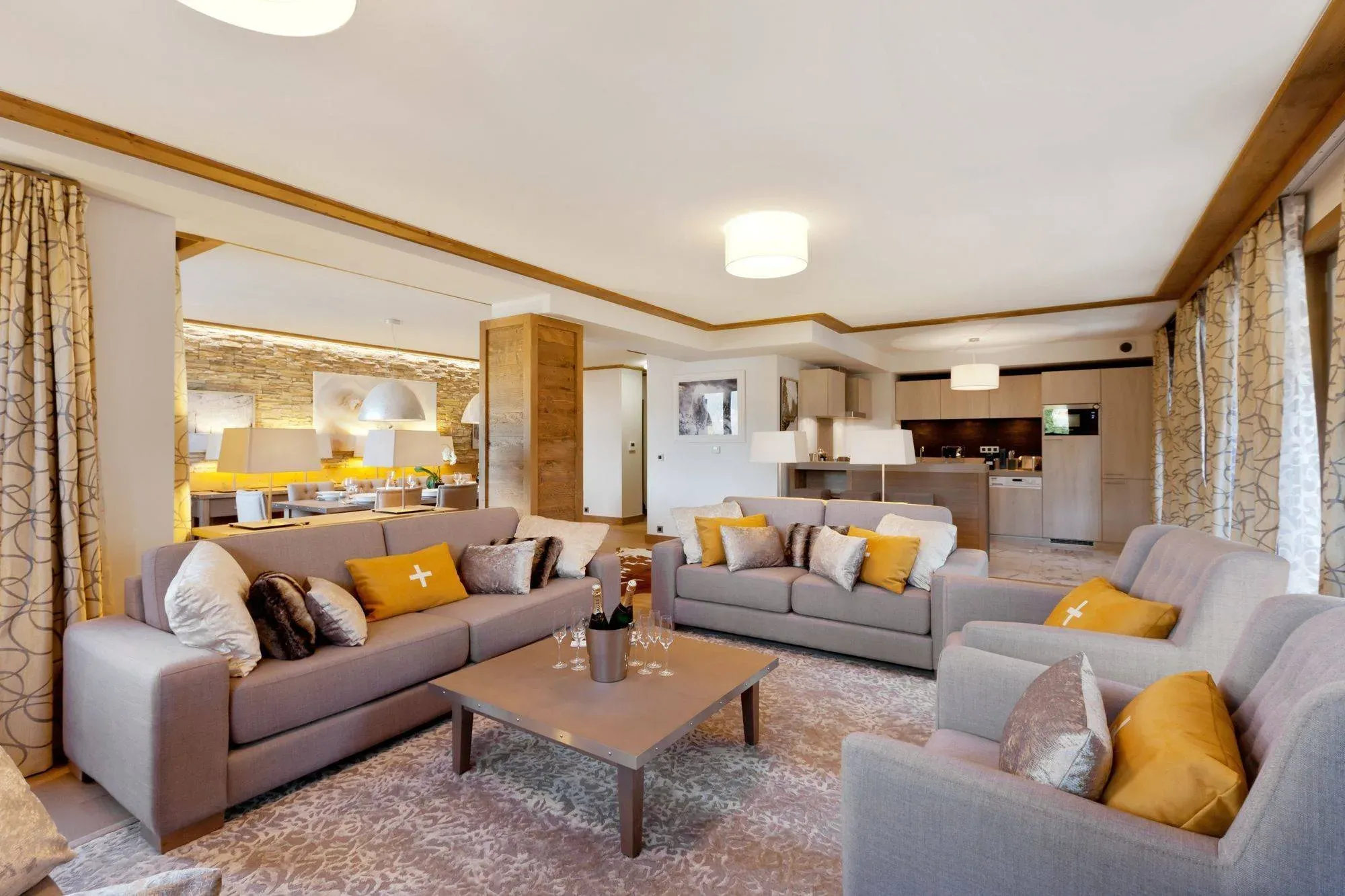 Living room with two grey sofas, two armchairs and open-plan kitchen behind