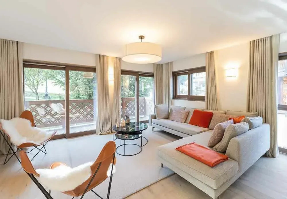 Living room with corner sofa, two leather butterfly chairs and balcony doors