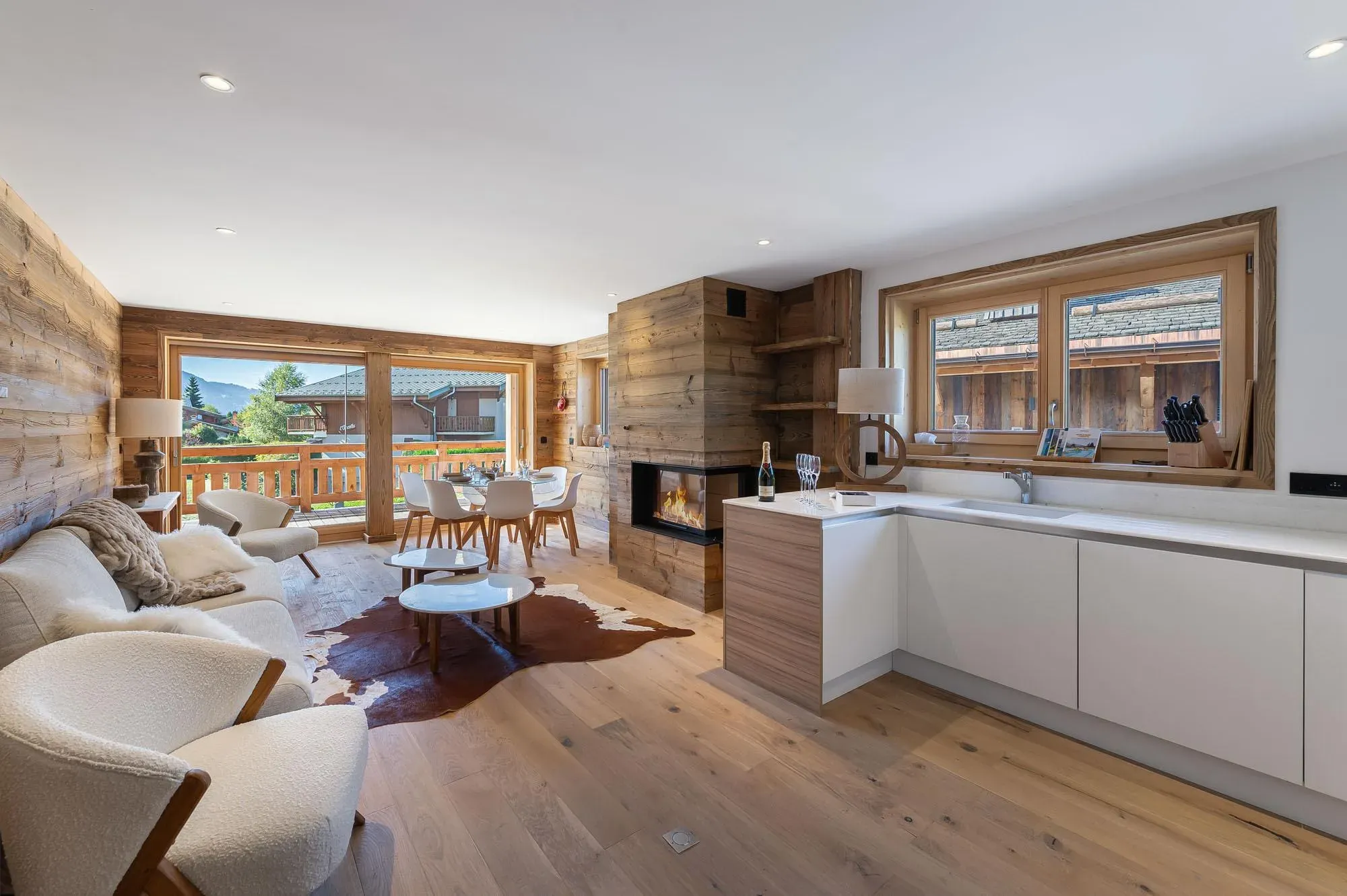 Open-plan living room with corner fireplace, sofa, cowhide rug and balcony doors