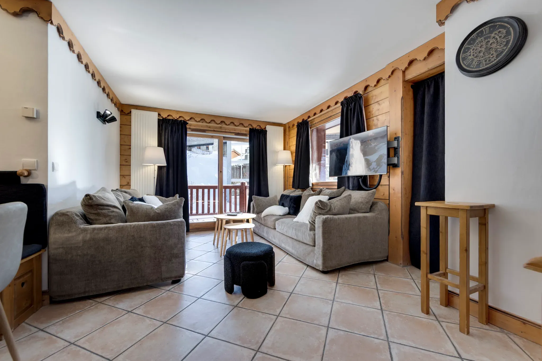 Living room with two grey sofas, wall-mounted TV and balcony doors