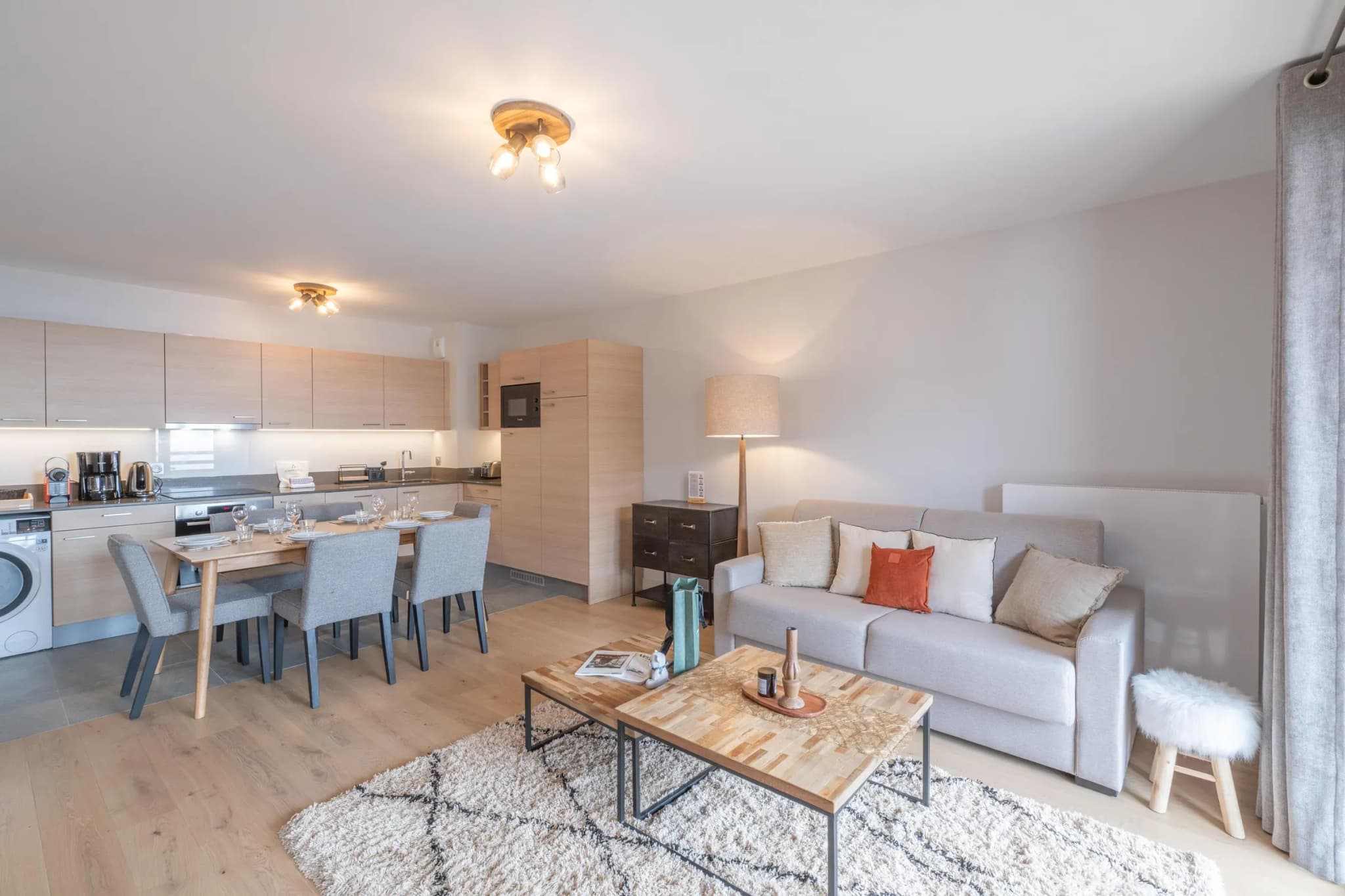 Open-plan living area with sofa bed, coffee tables and kitchen behind