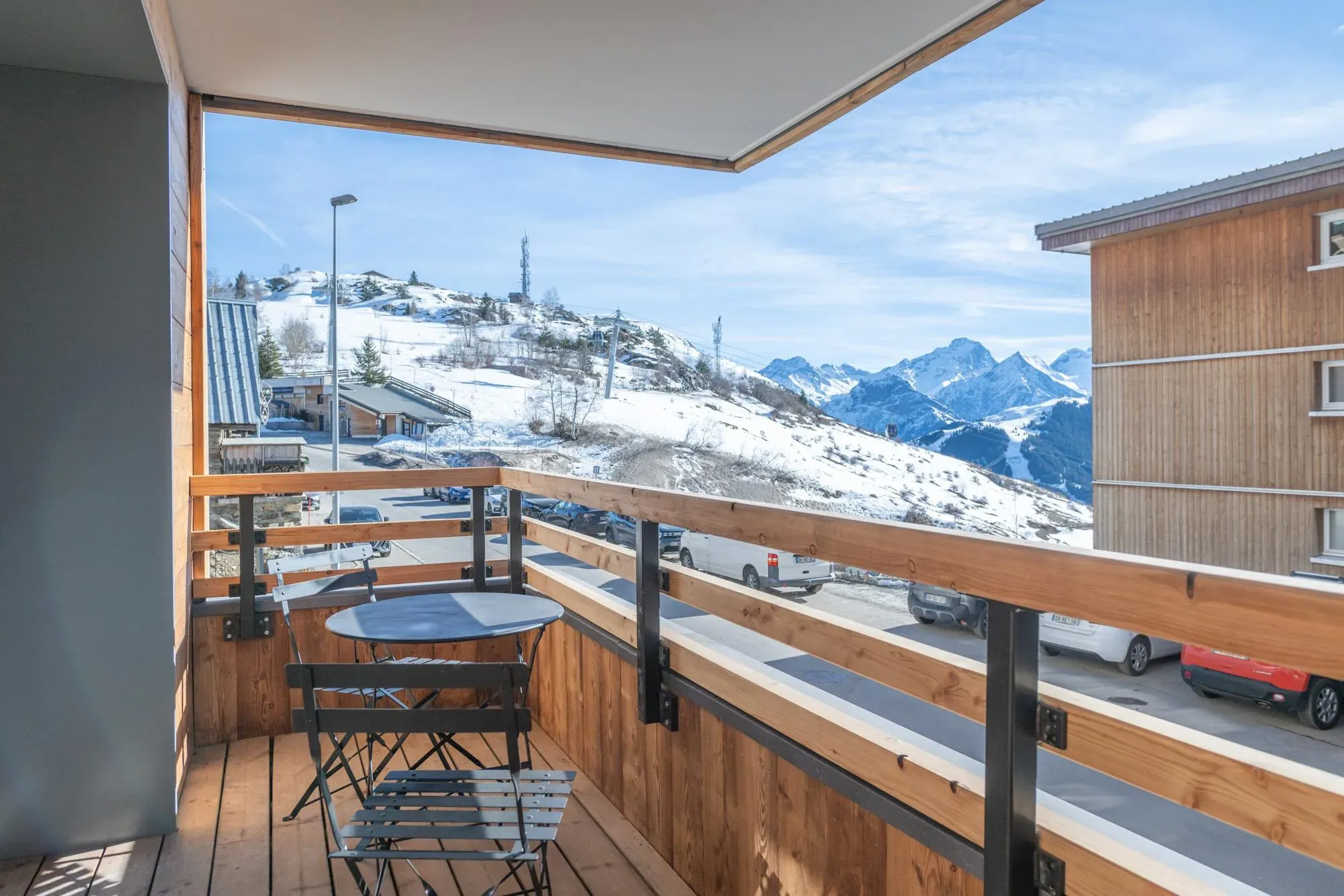 Balcony with bistro table and chairs facing snowy mountain views