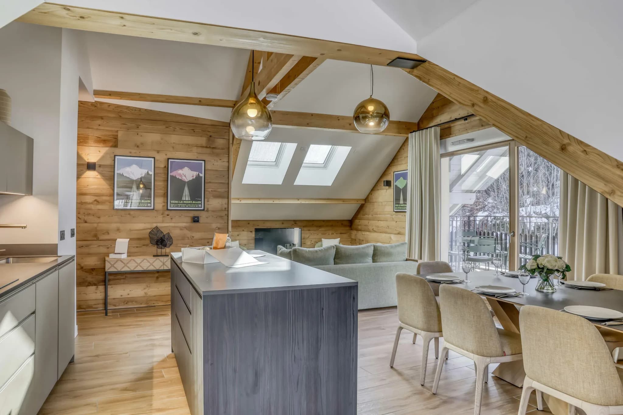 Open-plan kitchen with grey island, dining table for eight and sofa under exposed beams