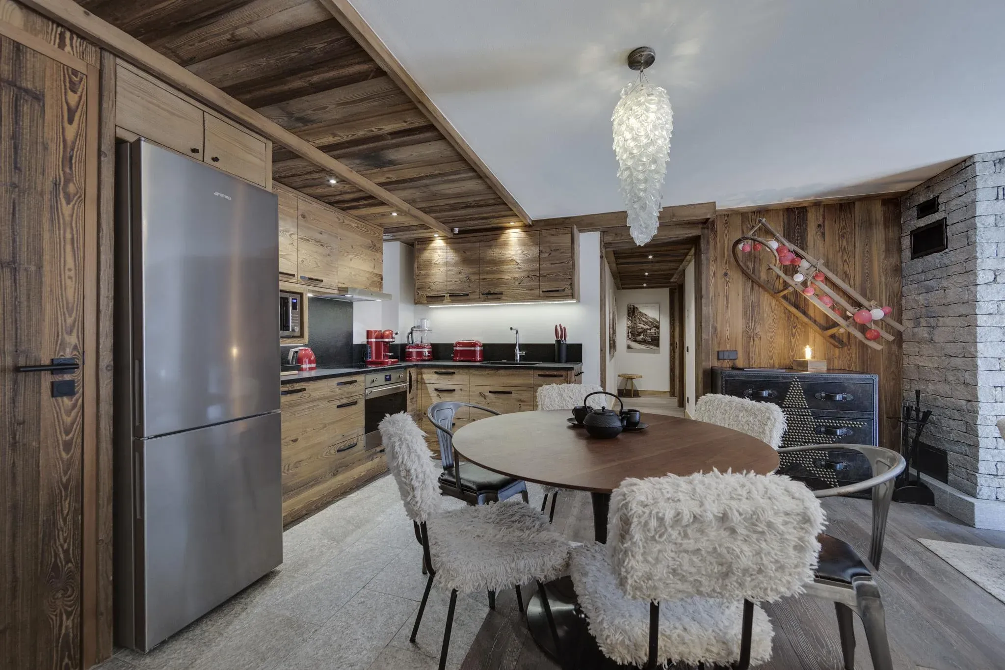 Kitchen and dining area with round table, four fur-covered chairs and steel fridge-freezer