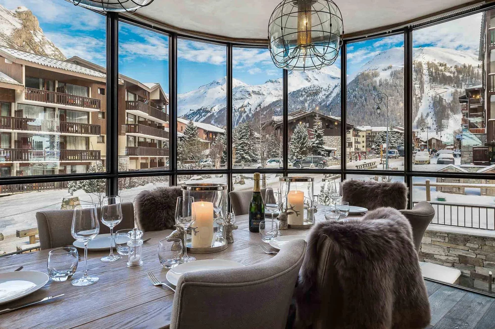 Dining area in a curved glass bay with round table and mountain views