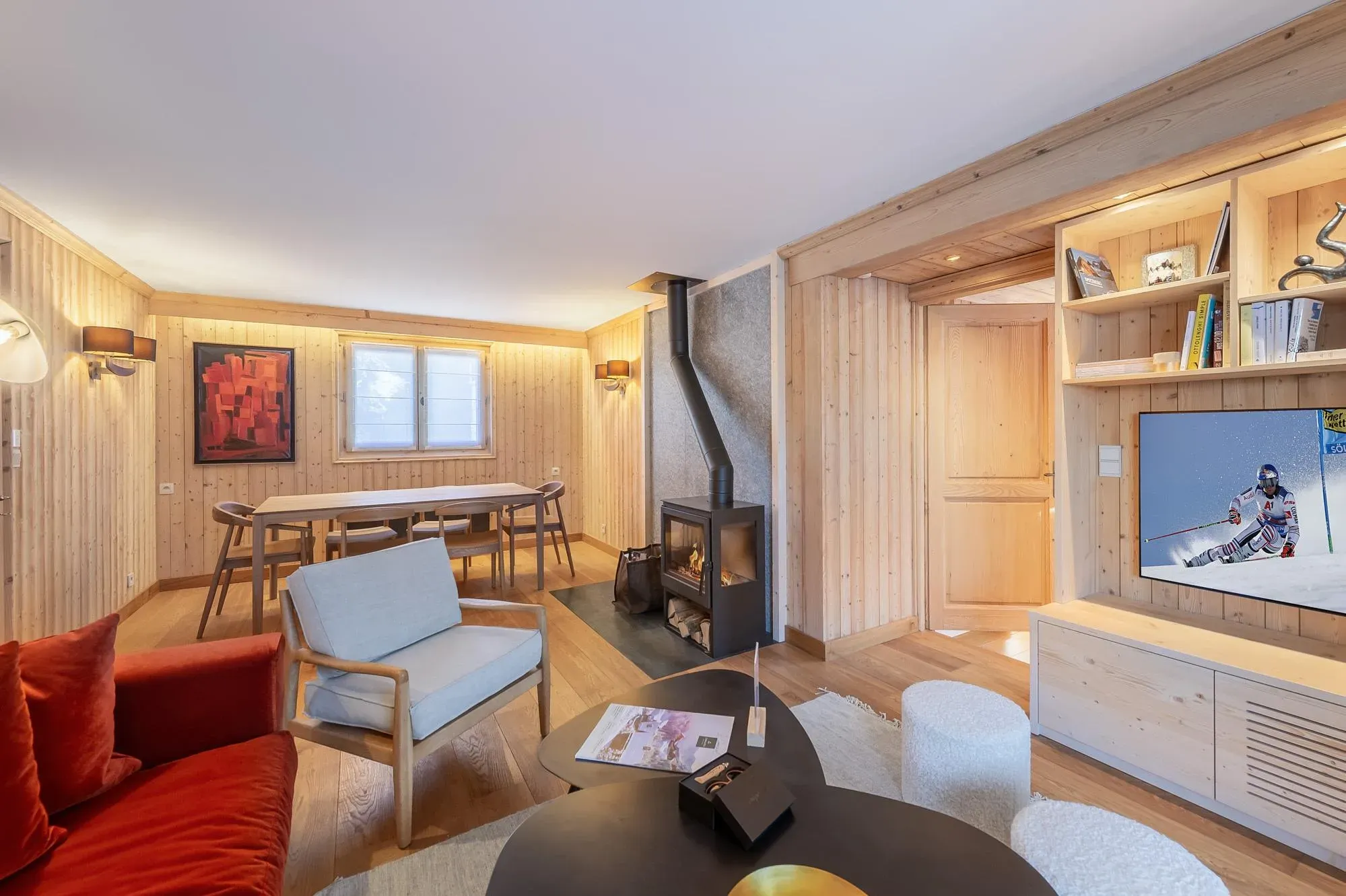 Living and dining area with wood stove, rust velvet sofa and six-seat dining table