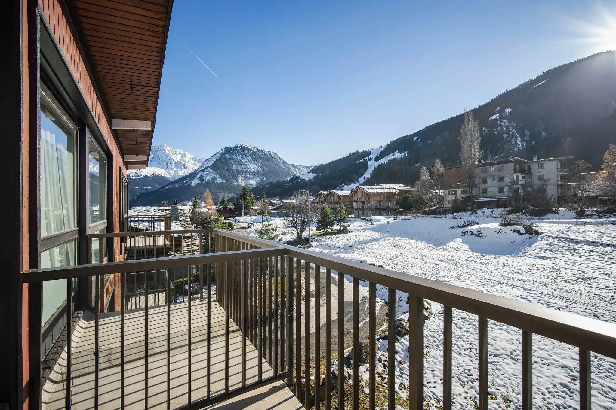 Balcony with railing overlooking snowy fields and mountains
