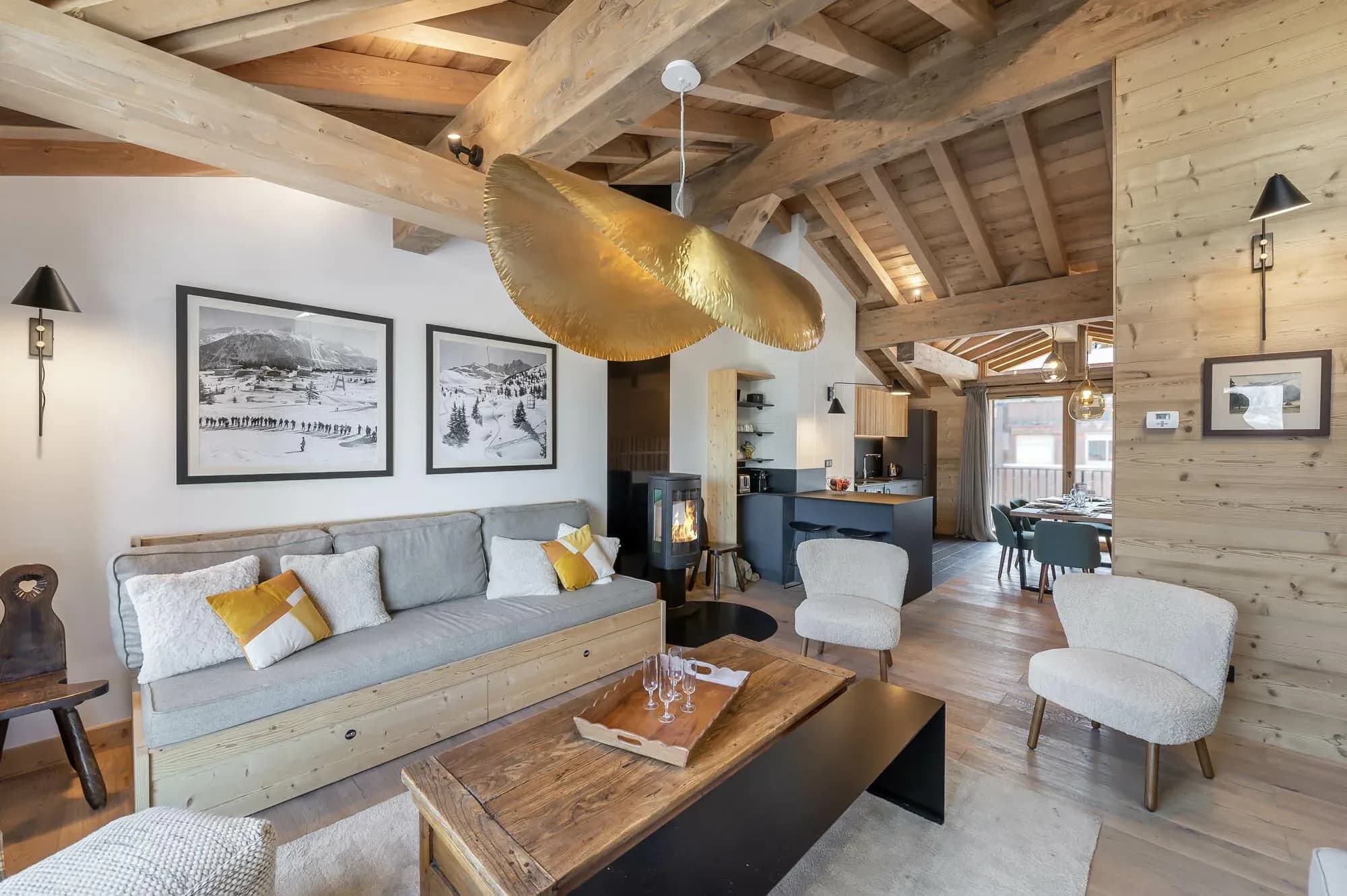 Living room with grey daybed sofa, wood burning stove and armchairs under exposed beams