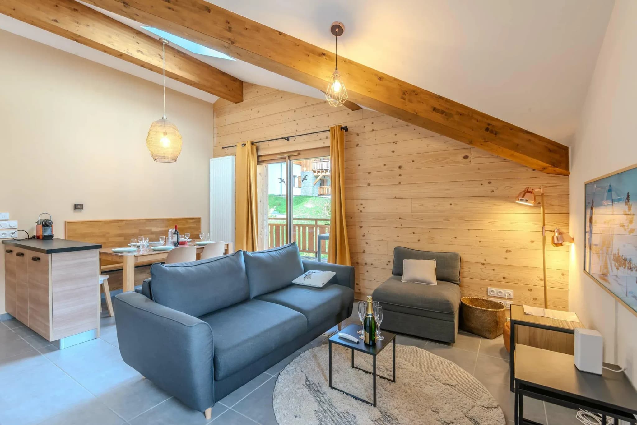Living area with grey sofa, armchair and sliding door to balcony