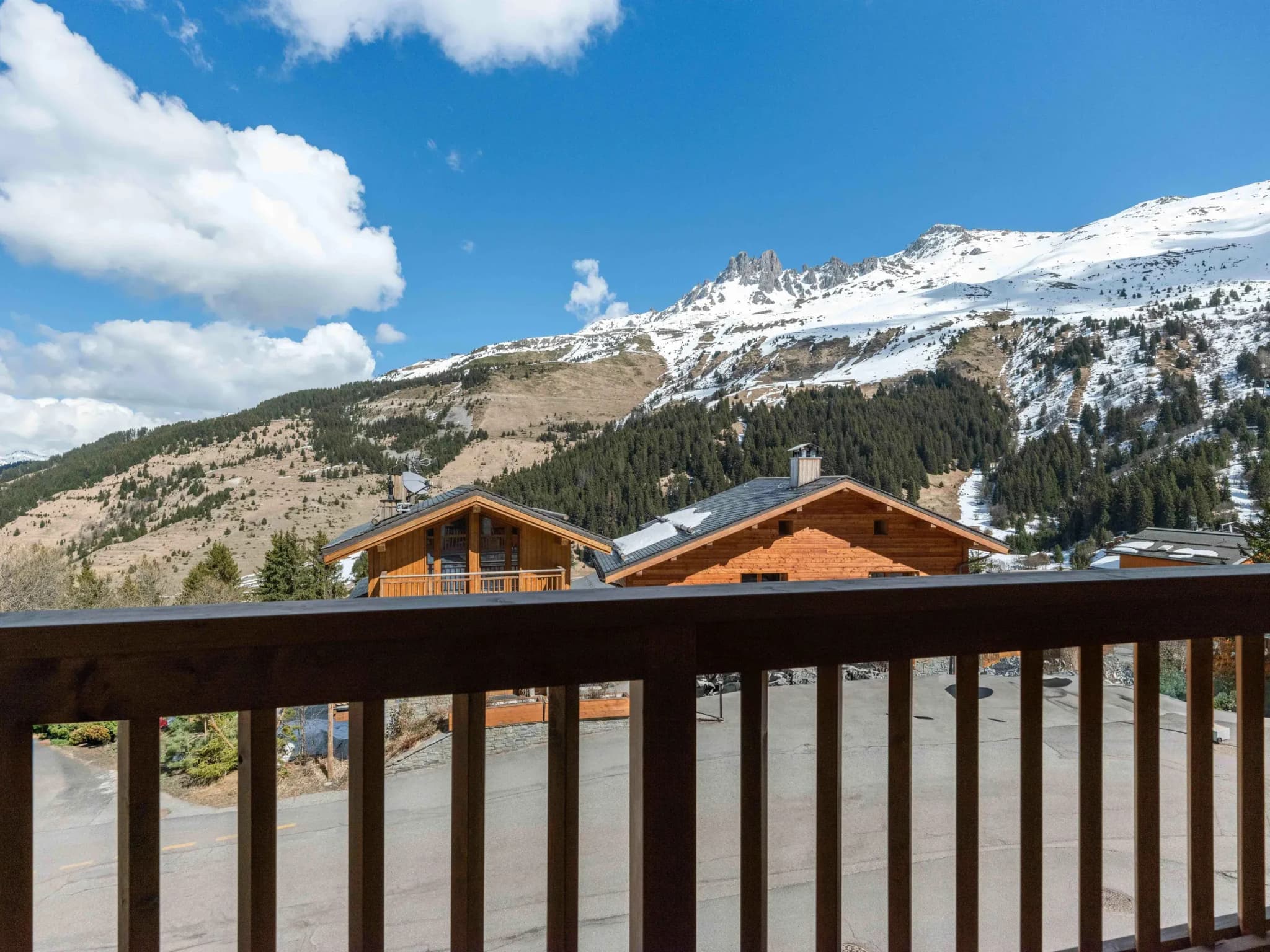 Balcony view of snowy peaks, wooded slopes and neighbouring chalets