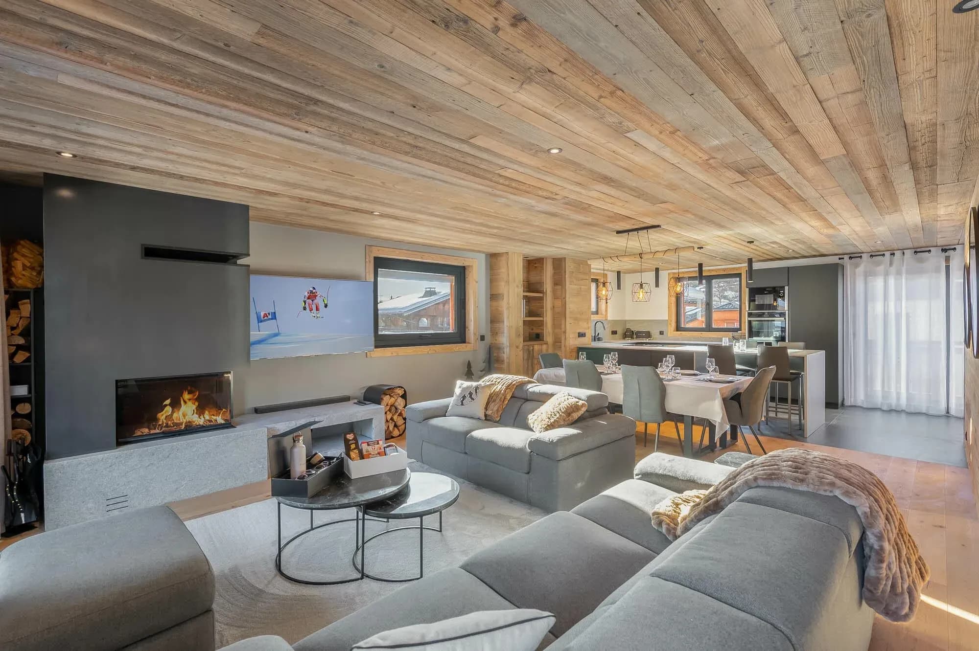 Open-plan living room with fireplace, grey sofas and dining table behind
