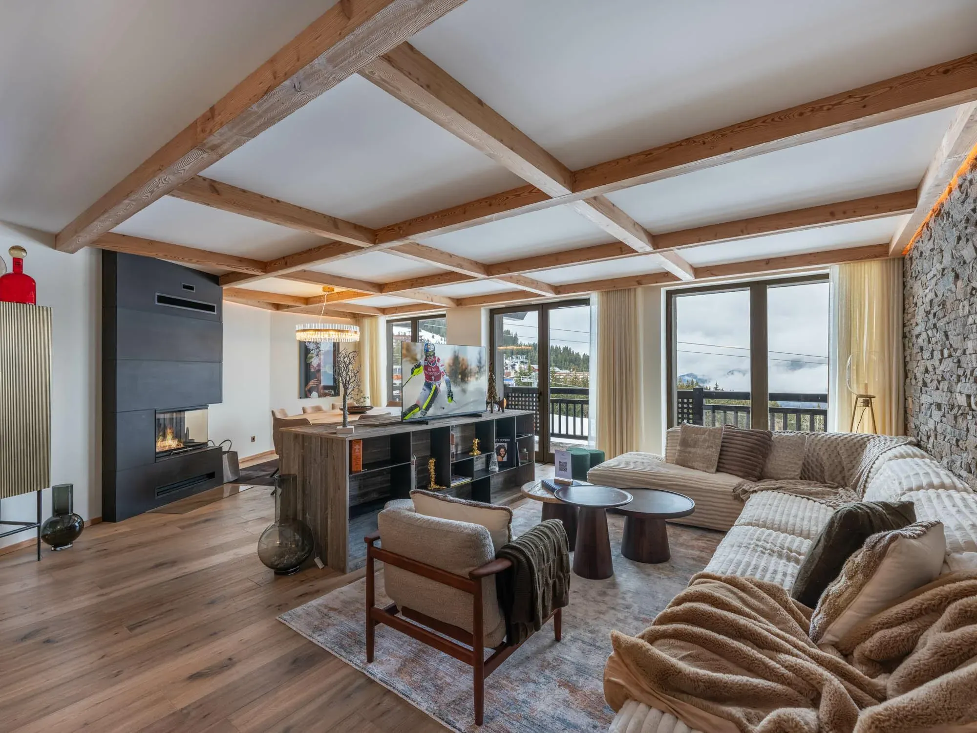 Living room with corner sofa, fireplace and balcony doors onto the slopes
