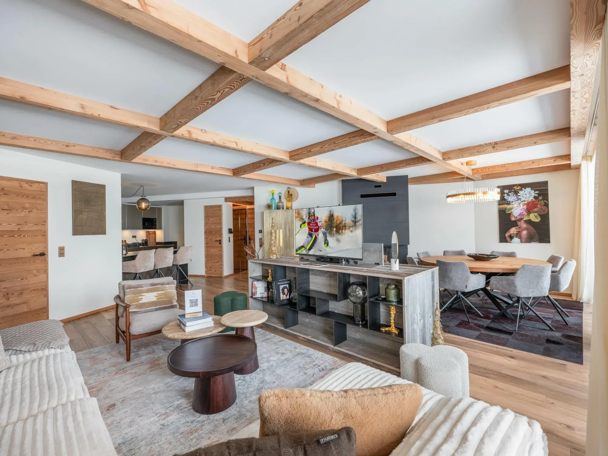 Open-plan lounge with exposed beams, sofa, armchair and dining table beyond
