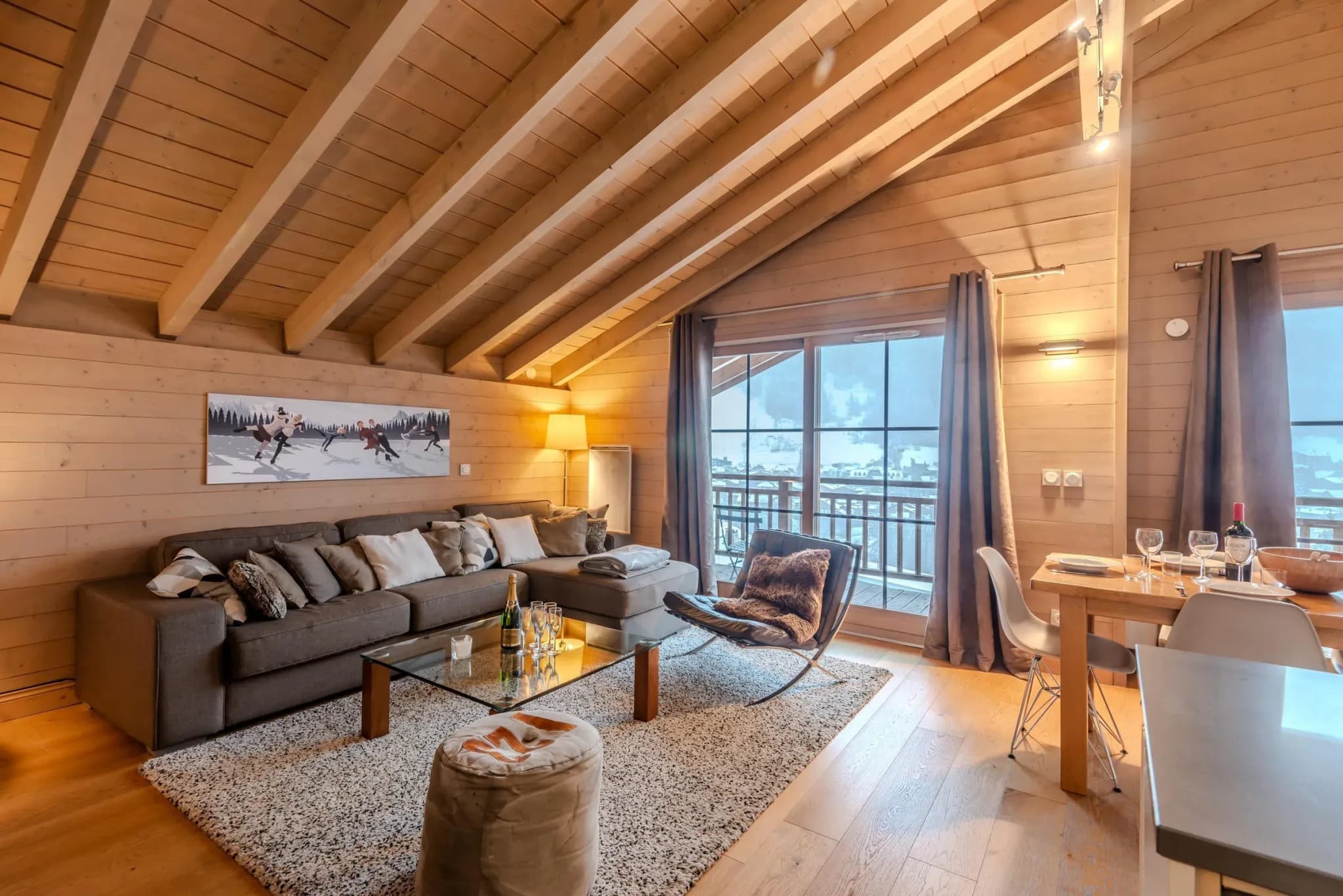 Living room with grey corner sofa, glass coffee table and balcony doors to mountain view