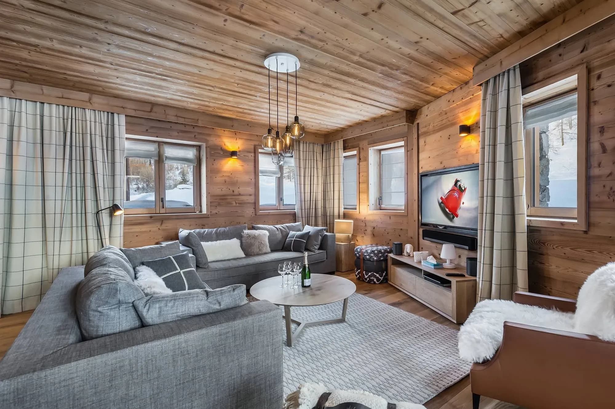 Living room with two grey sofas, wall-mounted TV and sheepskin armchair