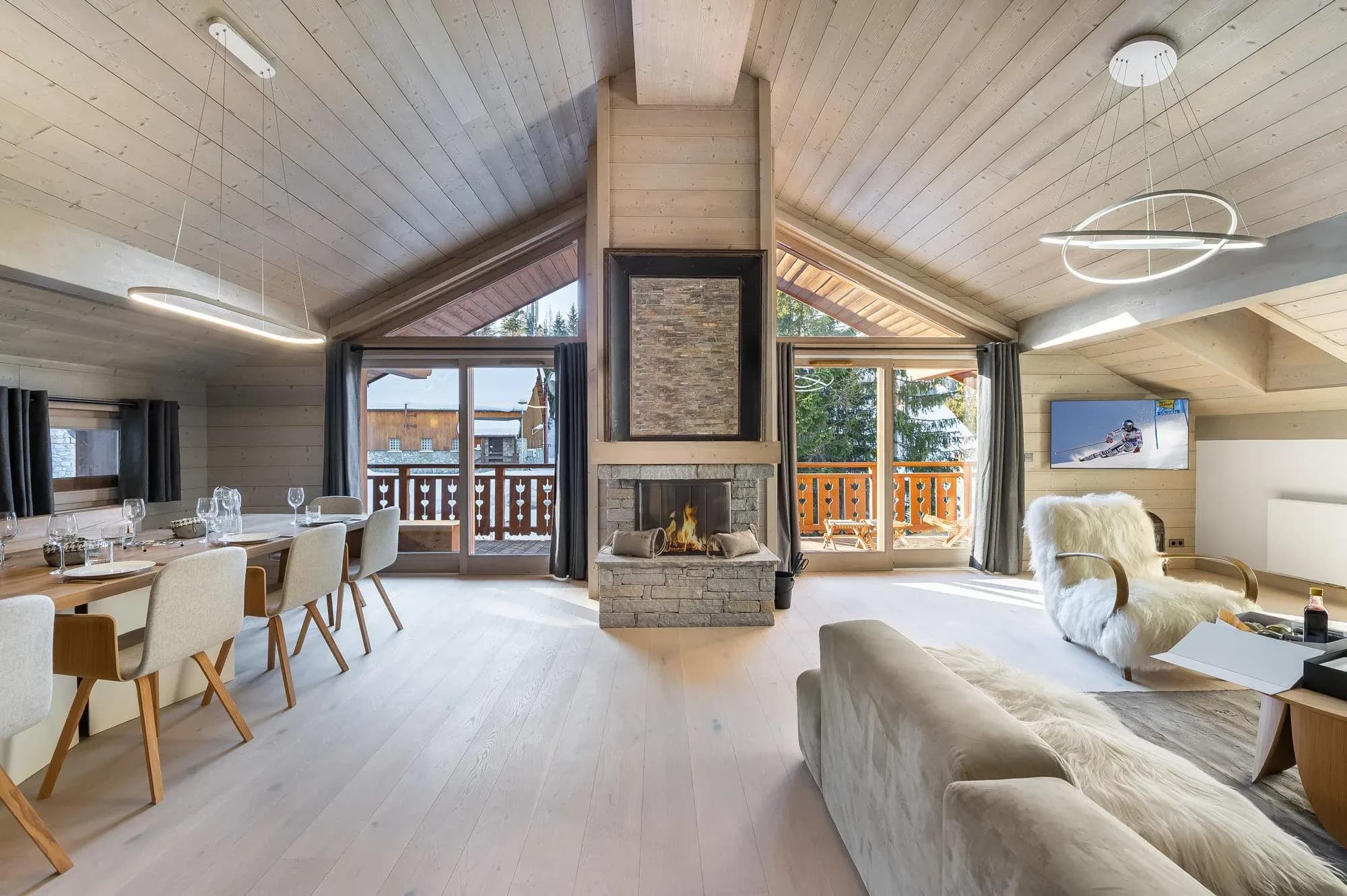 Open-plan living and dining area with stone fireplace and balcony doors