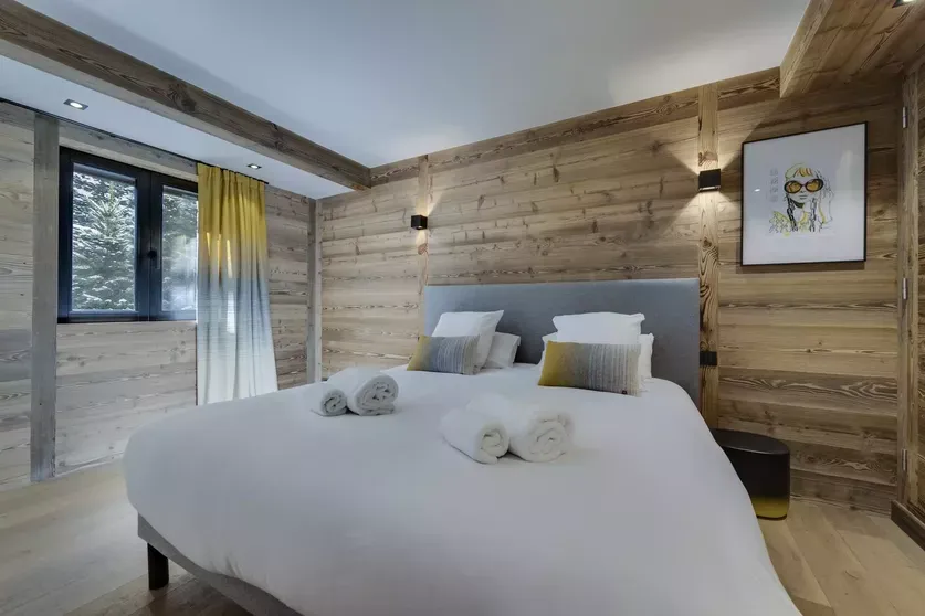 Double bedroom with timber walls and forest-facing window