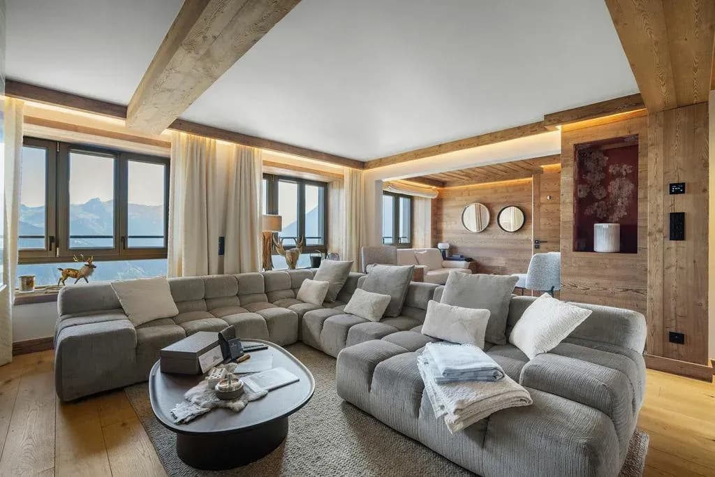 Living room with large grey sectional sofa and mountain views through wood-framed windows