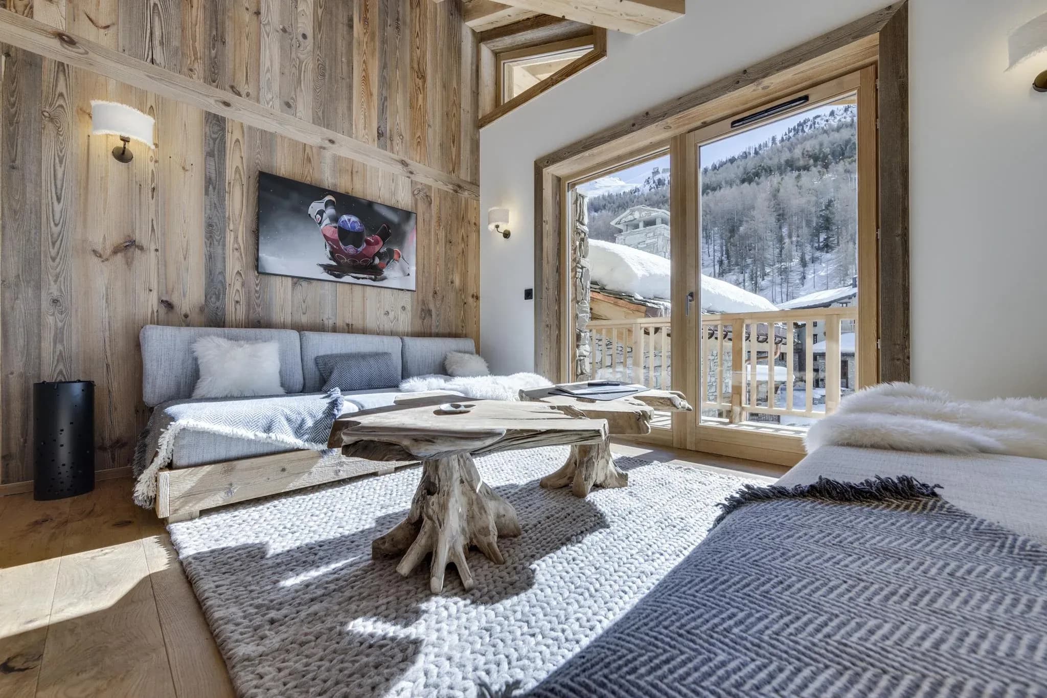 Living room with corner sofa, driftwood coffee tables and balcony doors to mountain view