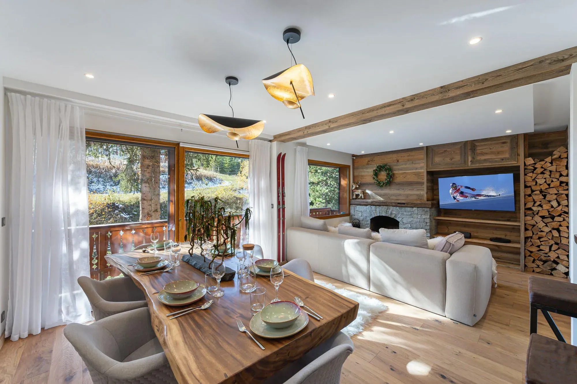 Dining area with live-edge wooden table and grey chairs, open to lounge with stone fireplace