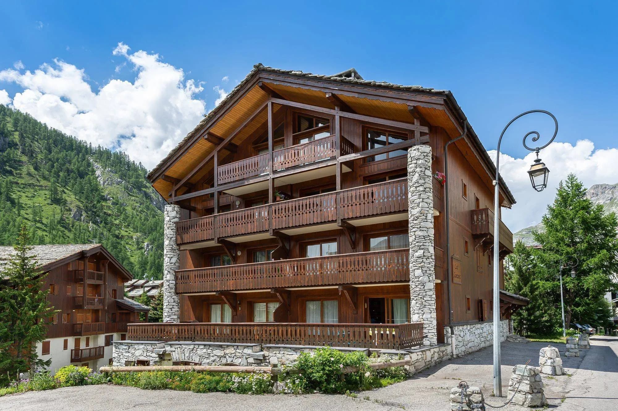 Wooden chalet building with stone columns and timber balconies on each floor