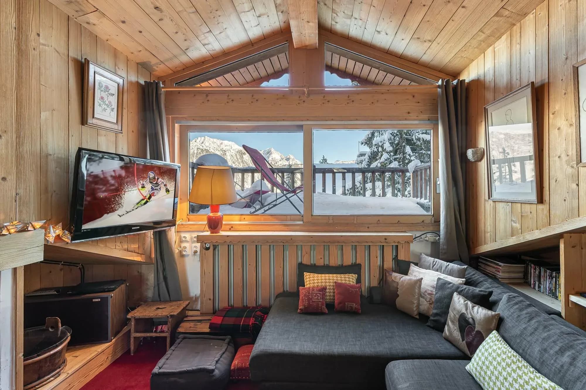 TV lounge with grey corner sofa and window onto snowy terrace